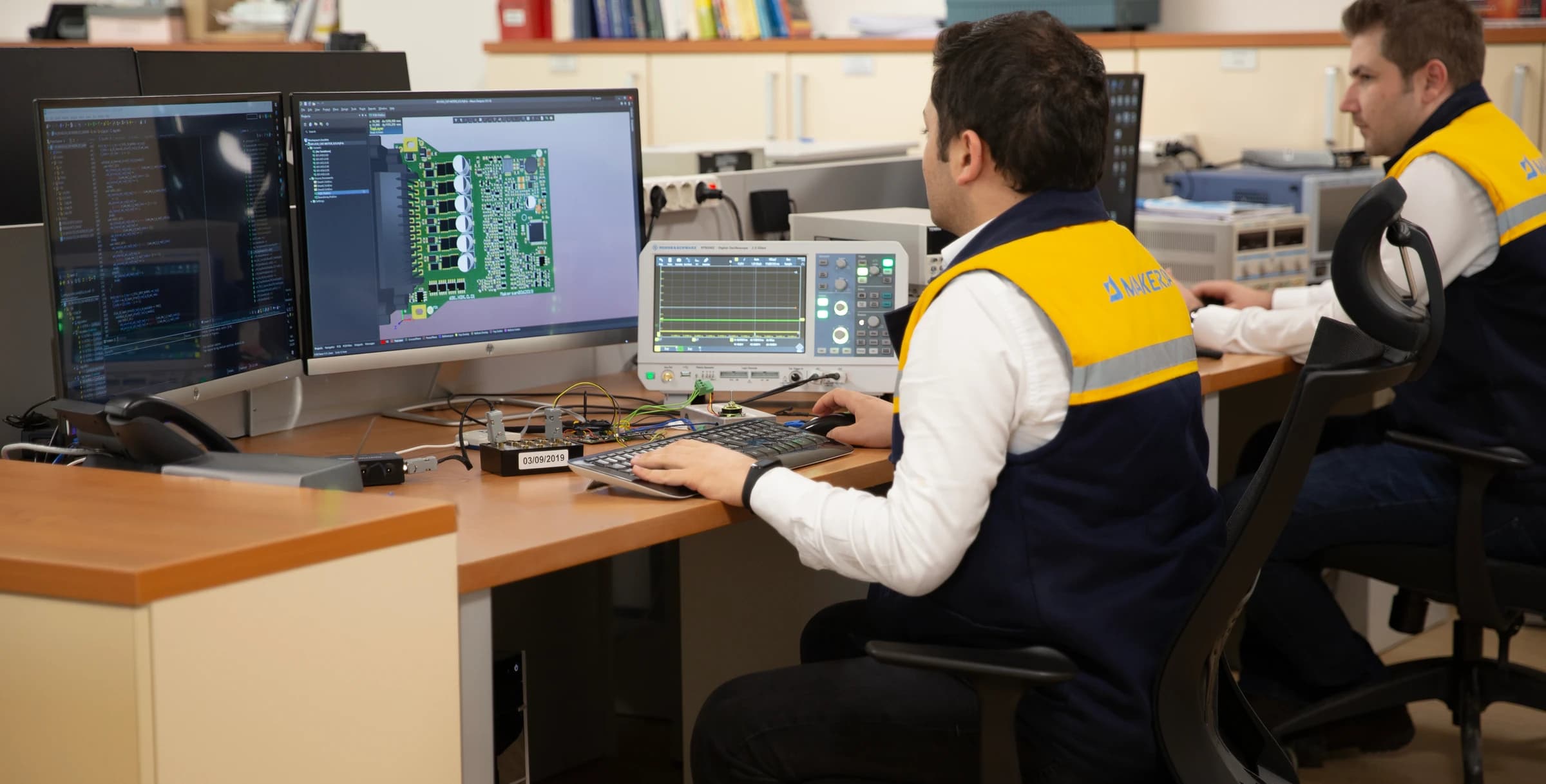 Makersan engineer working on a PCB layout next to bench measurement instruments