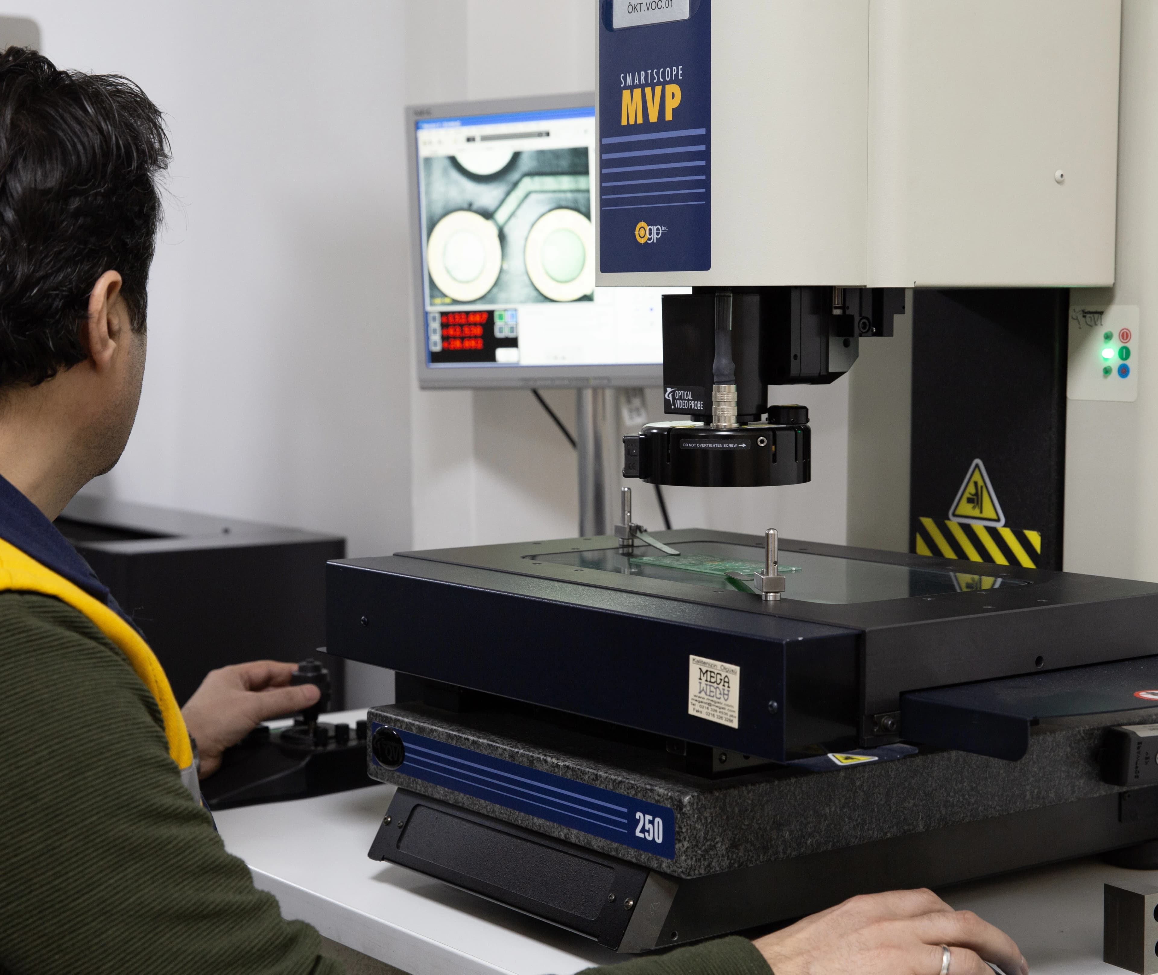 Operator measuring a populated circuit board on an OGP SmartScope optical measuring machine
